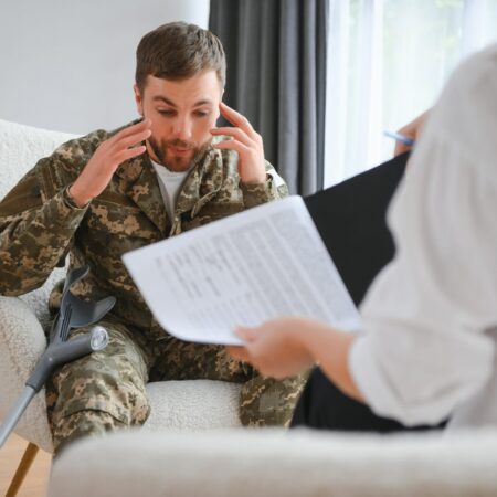 Sad male soldier on appointment with psychologist at office.